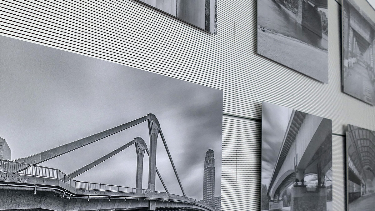 Eine Wand mit schwarz-weiß Fotografien, seitlich abfotografiert.