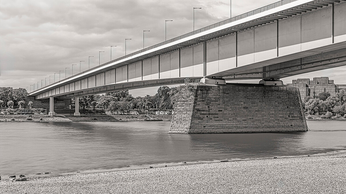 Eine Brücke über einem Fluss. Die Fotografie ist in schwarz-weiß gehalten.