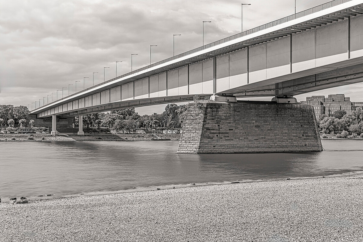 Eine Brücke über einem Fluss. Die Fotografie ist in schwarz-weiß gehalten.