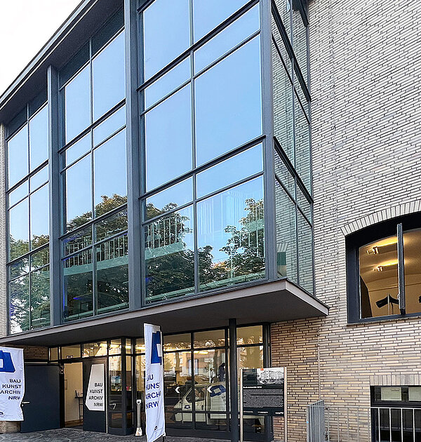 Ein Gebäude im Anschnitt mit heller Fassade, teilweise mit Glaselementen.