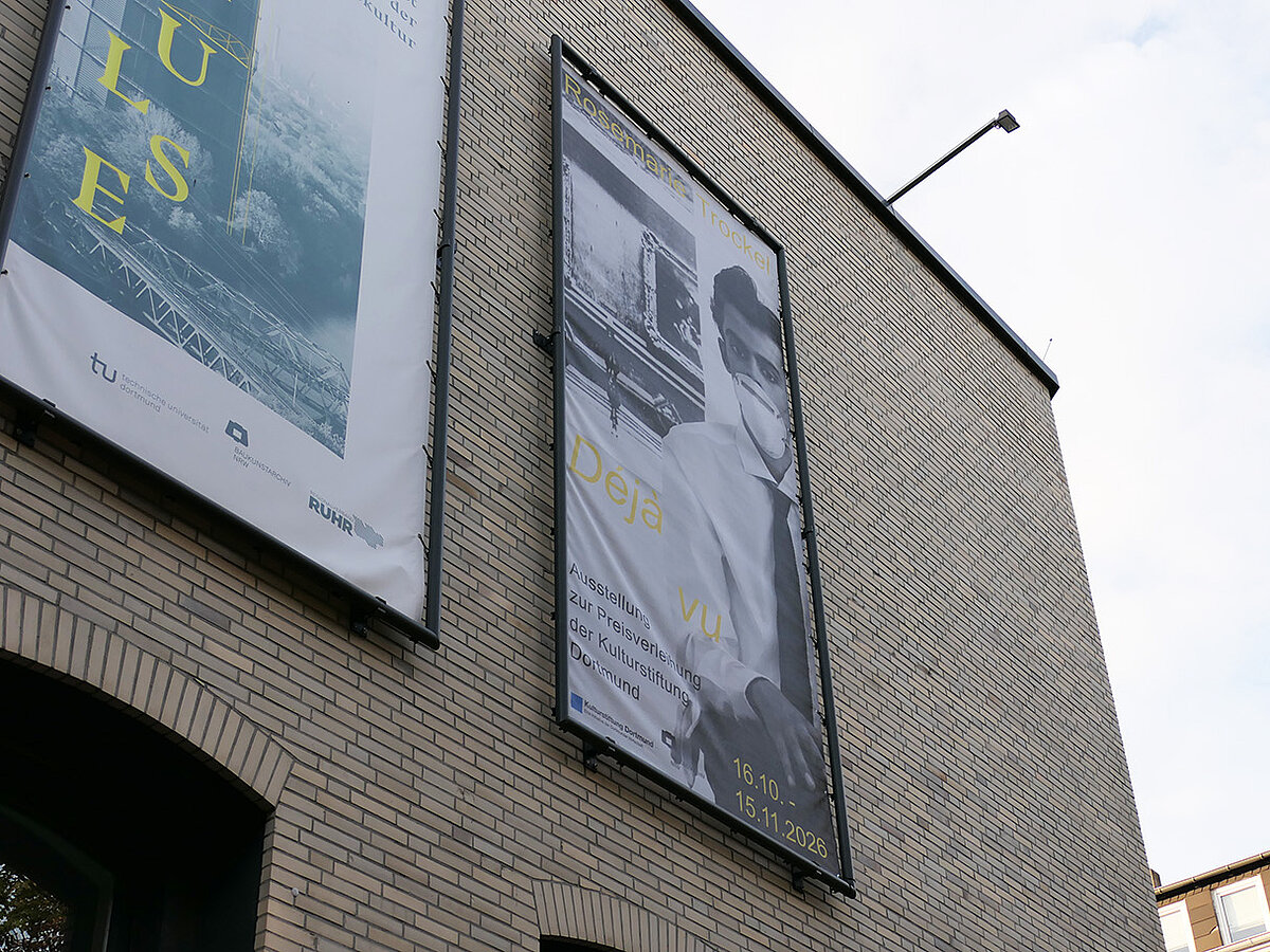 Anschnitt einer Außenfassade eines Gebäudes, dieses ist mit mehreren Bannern behangen.