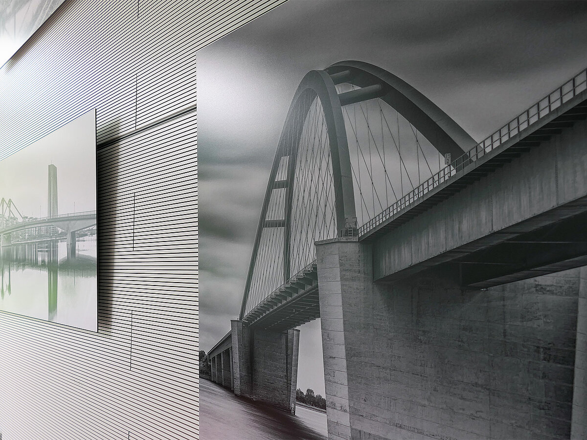 Eine Wand mit schwarz-weiß Fotografien, seitlich abfotografiert.