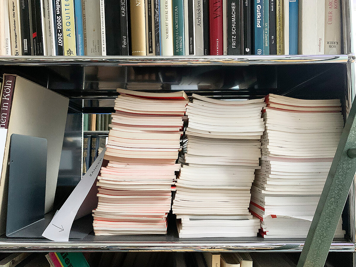 Zahlreiche Bücher liegen und stehen in mehreren Regalen.