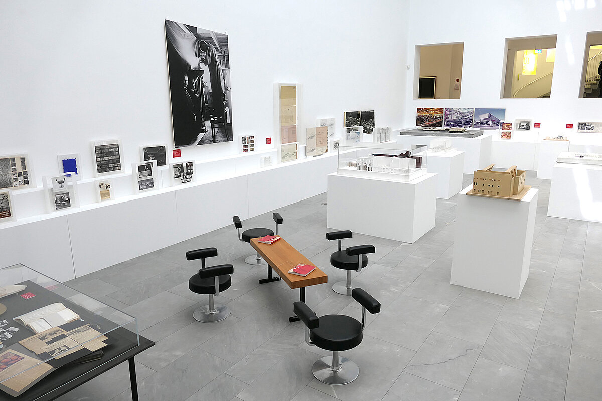 Blick in einen hellen Ausstellungsraum, hier stehen Möbel und Text- und Bildttafeln.