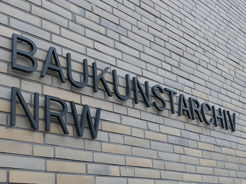 Blick auf eine helle Gebäudefassade mit der Aufschrift "Baukunstarchiv NRW".