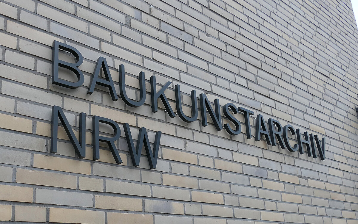 Blick auf eine helle Gebäudefassade mit der Aufschrift "Baukunstarchiv NRW".