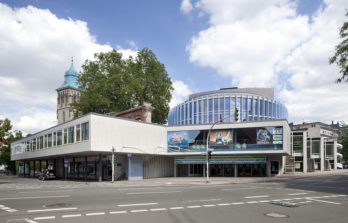 Ein Gebäude an einer Straße, vereinzelt sind Bäume drumherum zu erkennen.
