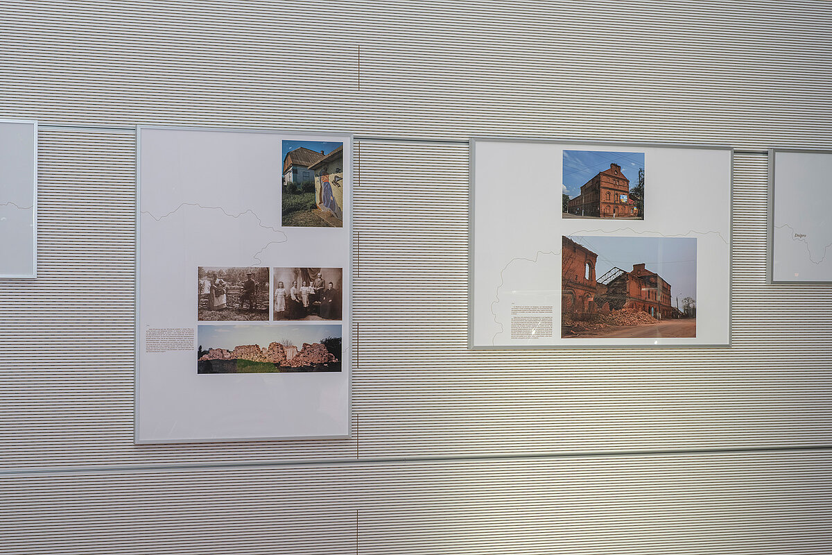 Blick in eine Ausstellung mit gerahmten Fotografien und Informationstafeln.