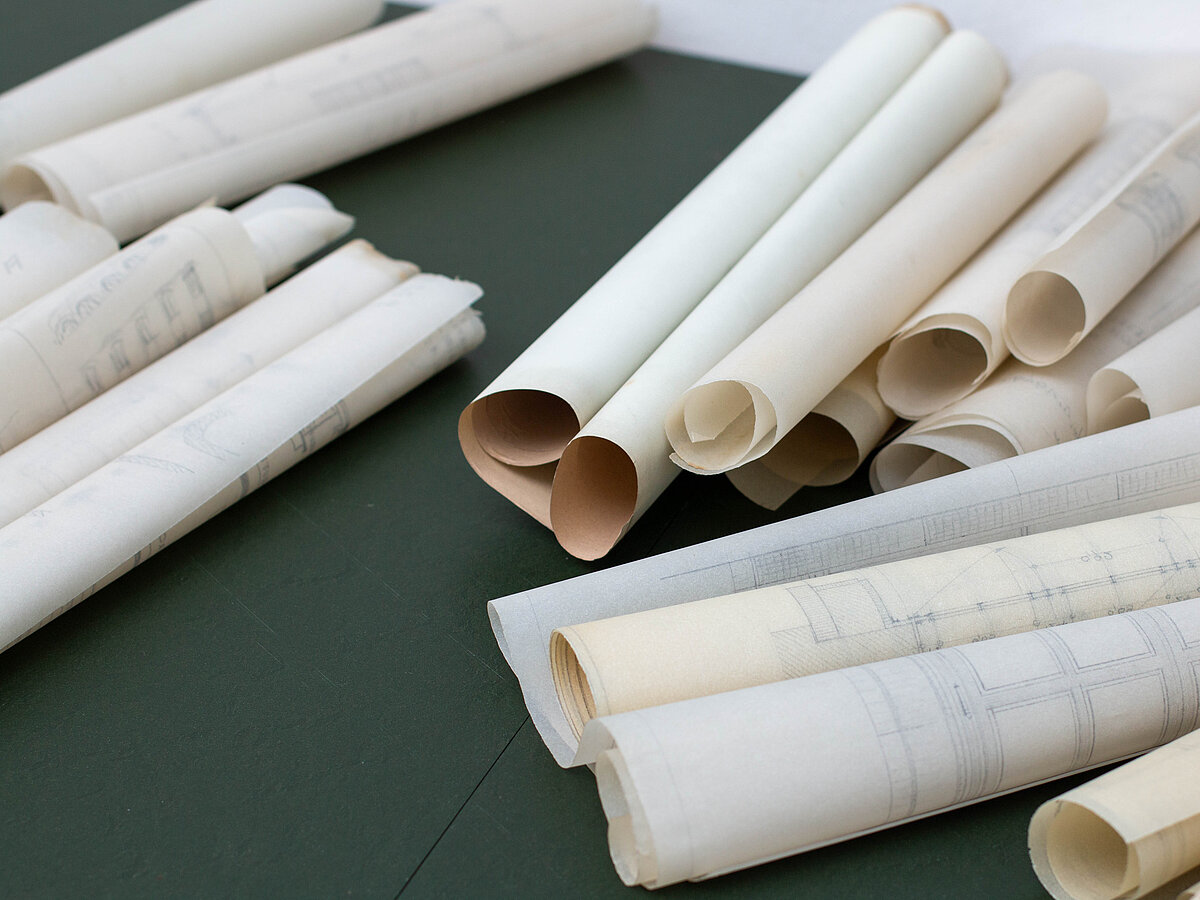 Baupläne aus Papier liegen aufgerollt nebeneinander.